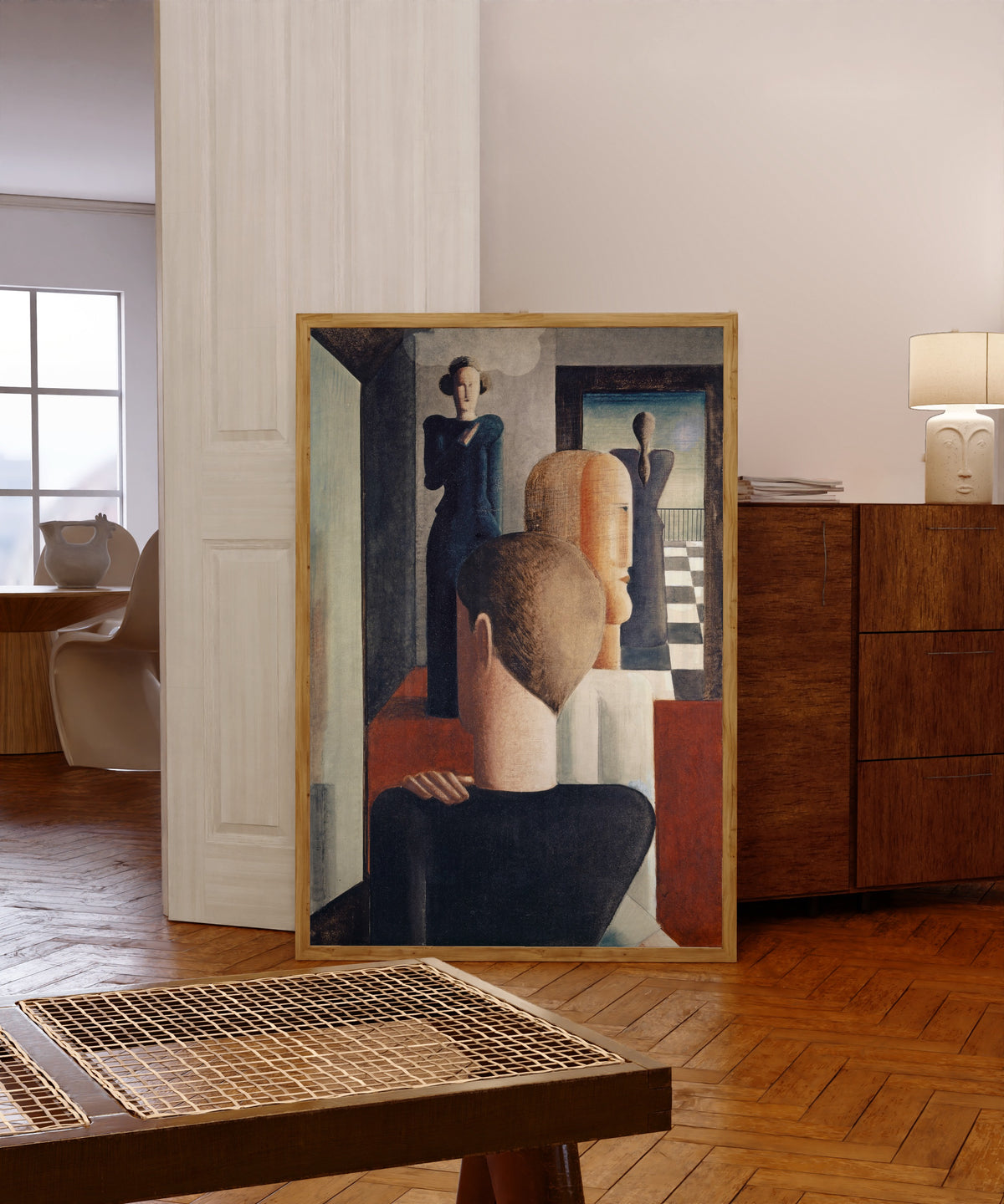 Framed art print of Interior with Five Figures, Roman by Oskar Schlemmer, in a light wood frame leaning in a warm room with a parquet floor