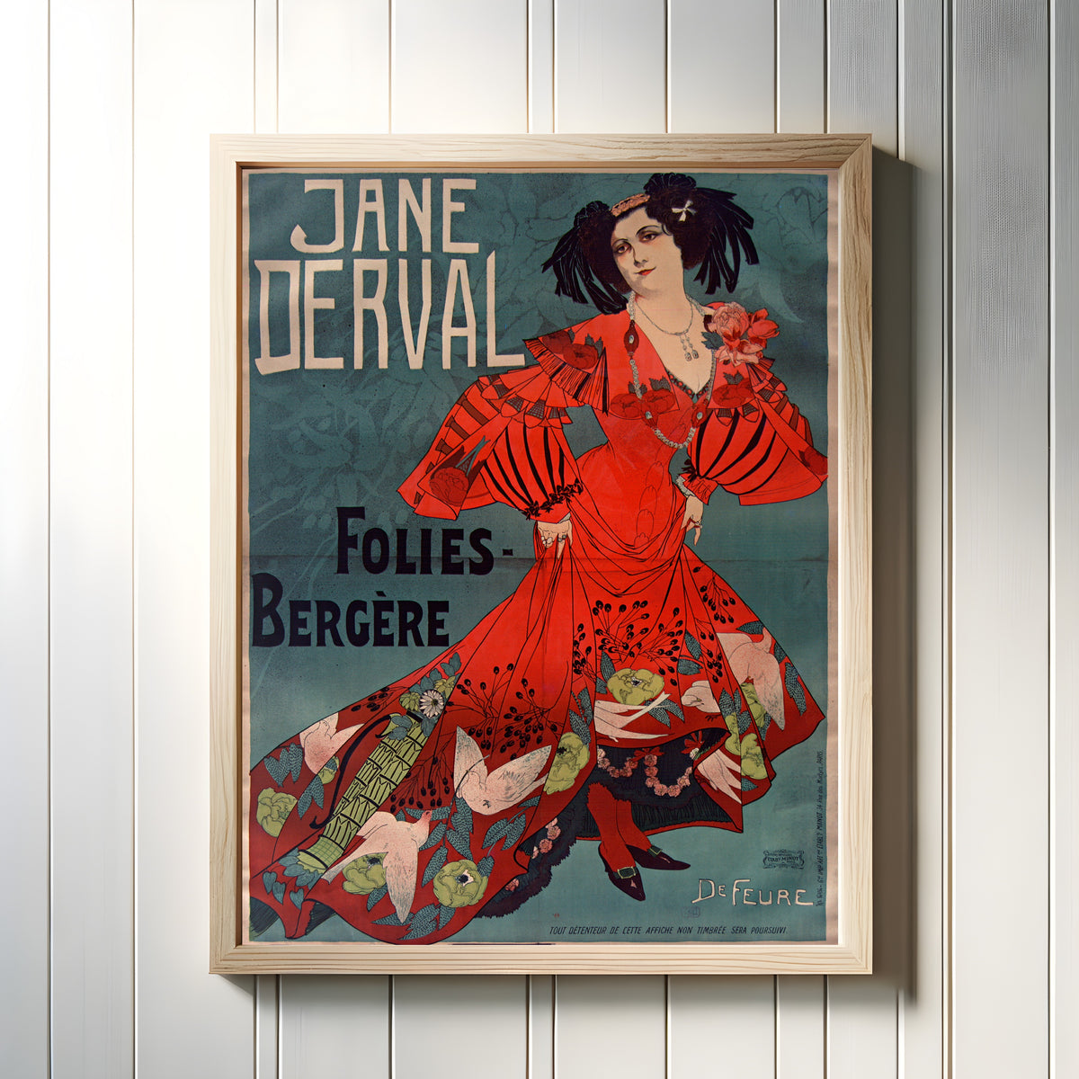Framed art print of Jane Derval, Folies-Bergère by Georges de Feure, in a light wood frame on a white panelled wall