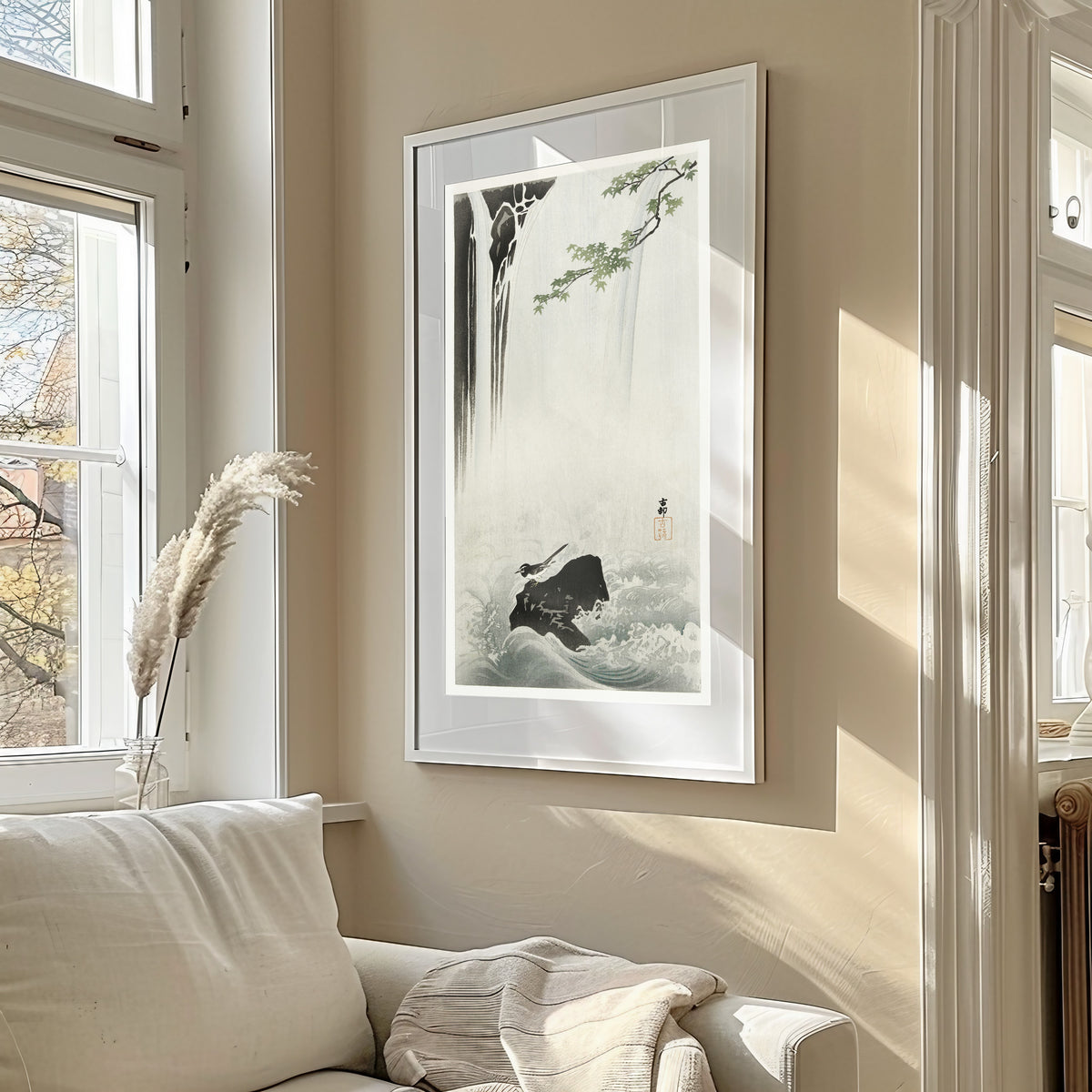 Framed art print of Japanese Wagtail at a Waterfall by Ohara Koson, in a sunlit living room above a sofa