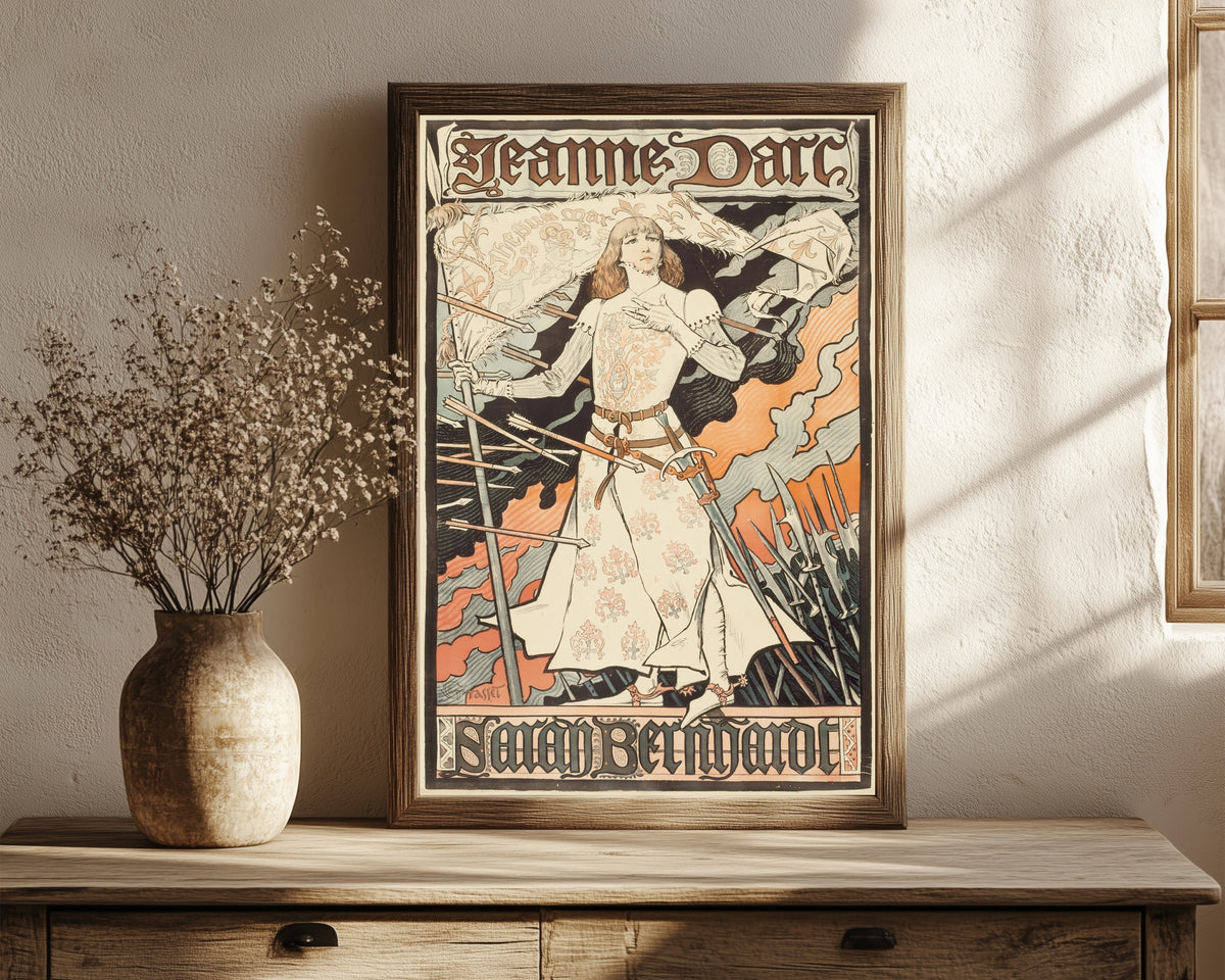 Framed art print of Jeanne d'Arc-Sarah Bernhardt by Eugène Grasset, in a dark wood frame leaning on a rustic console beside dried flowers