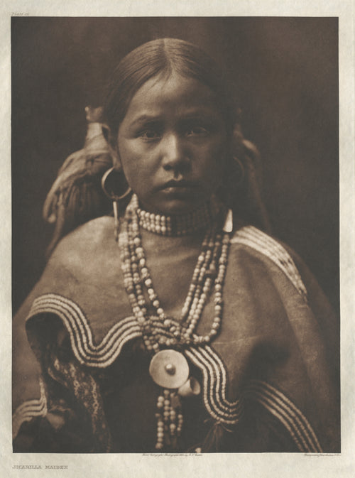 Jicarilla Maiden by Edward S. Curtis — A young woman in hoop earrings and strands of beads meets our gaze