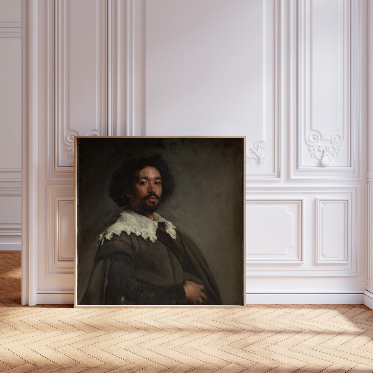 Framed art print of Juan de Pareja by Diego Velázquez, leaning against pale pink panelling on a herringbone floor