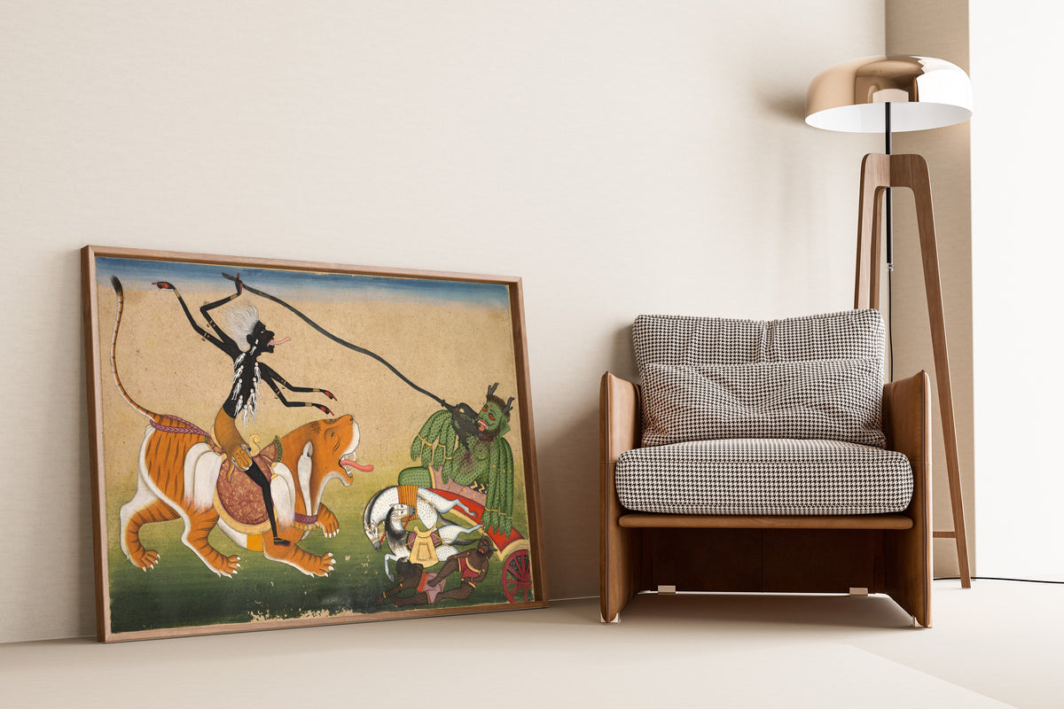 Framed art print of Kali Attacking Nisumbha by Pahari school, leaning against a wall beside an armchair and a floor lamp