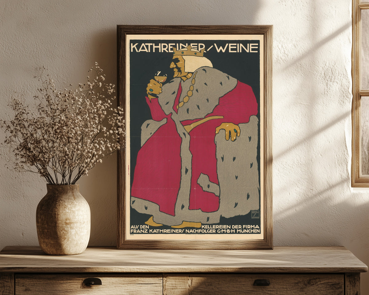 Framed art print of Kathreiner Weine by Ludwig Hohlwein, in a dark wood frame leaning on a rustic console beside dried flowers