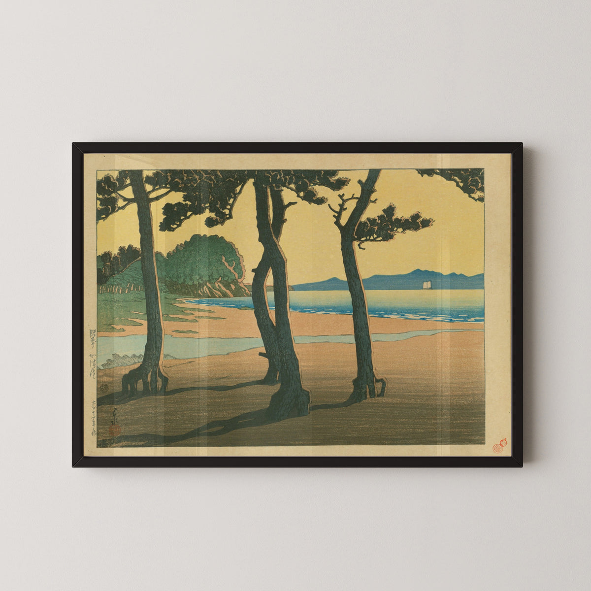 Framed art print of Kazusa Beach in Hizen Province by Kawase Hasui, in a black frame on a pale wall