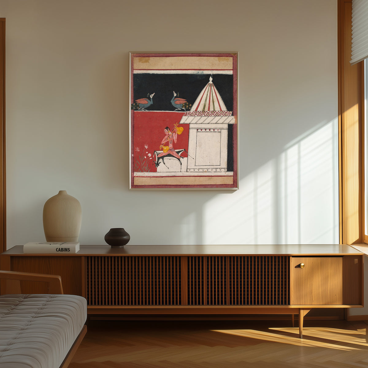 Framed art print of Kedara Ragini by Malwa school, in a thin light frame on a sunlit wall above a wooden sideboard