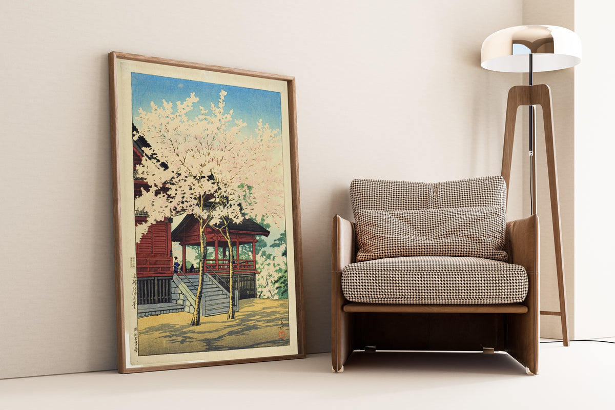 Framed art print of Kiyomizu Hall, Ueno by Kawase Hasui, leaning against a wall beside an armchair and a floor lamp