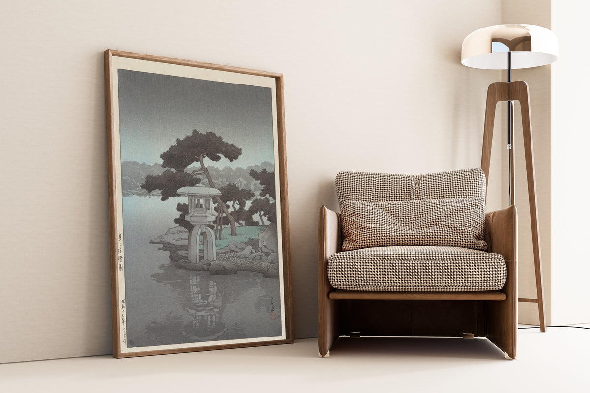 Framed art print of Kiyozumi Garden in Moonlight by Kawase Hasui, leaning against a wall beside an armchair and a floor lamp