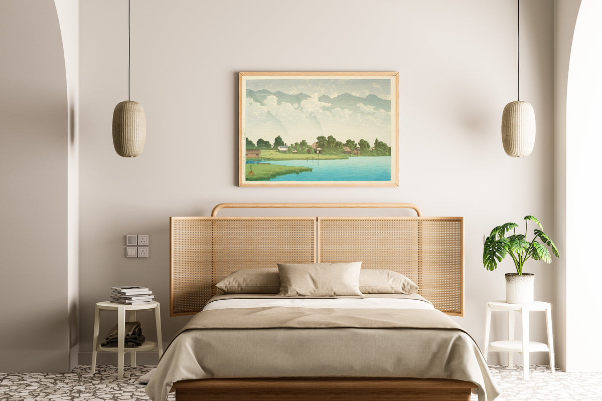Framed art print of Kizaki Lake in Shinshu by Kawase Hasui, above a cane-headboard bed