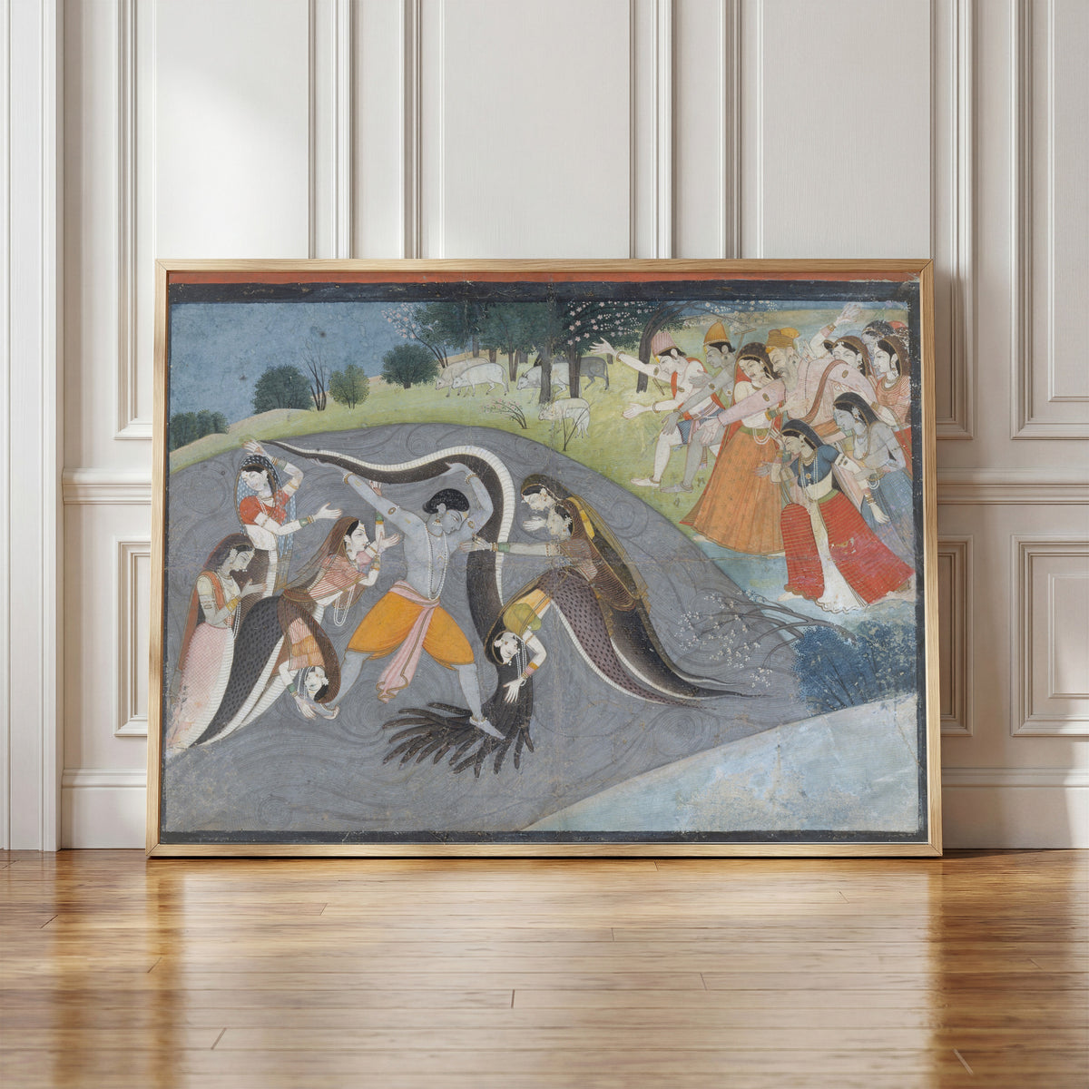 Framed art print of Krishna Subduing Kaliya, the Snake Demon: Folio from a… by Garhwal school, in a light wood frame leaning against a panelled white wall