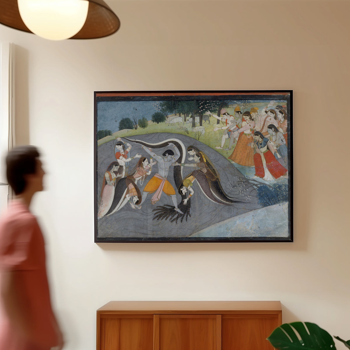 Framed art print of Krishna Subduing Kaliya, the Snake Demon: Folio from a Bhagavata… by Garhwal school, in a slim black frame on a warm wall in a sunlit room