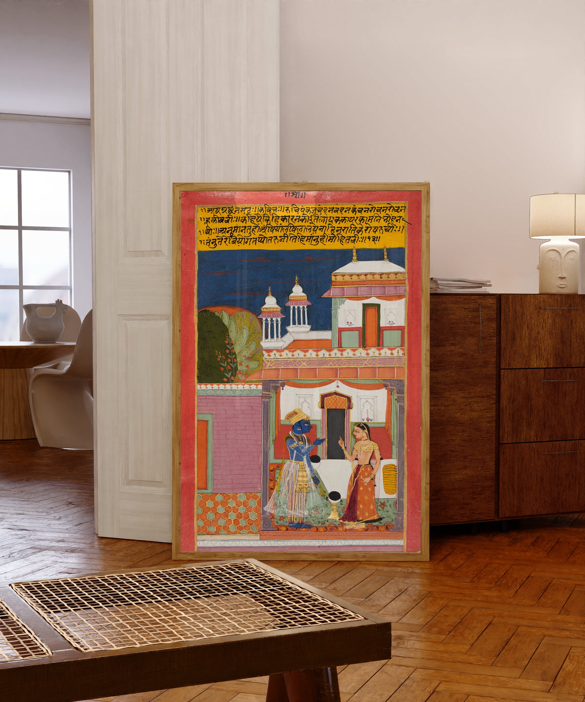 Framed art print of Krishna and Radha Quarreling: Shatha Nayaka, from a… by Bundi school, in a light wood frame leaning in a warm room with a parquet floor