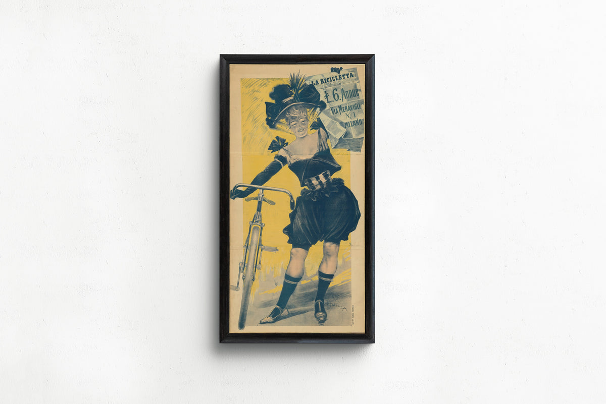 Framed art print of La Bicicletta by Aleardo Villa, in a slim black frame on a plain white wall