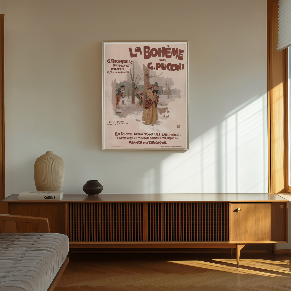 Framed art print of La Bohème de G. Puccini by Adolfo Hohenstein, in a thin light frame on a sunlit wall above a wooden sideboard