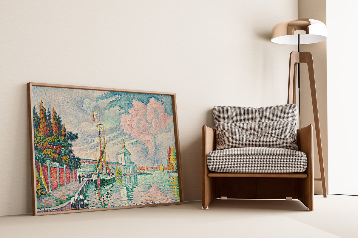 Framed art print of La Dogana, Venice by Paul Signac, leaning against a wall beside an armchair and a floor lamp