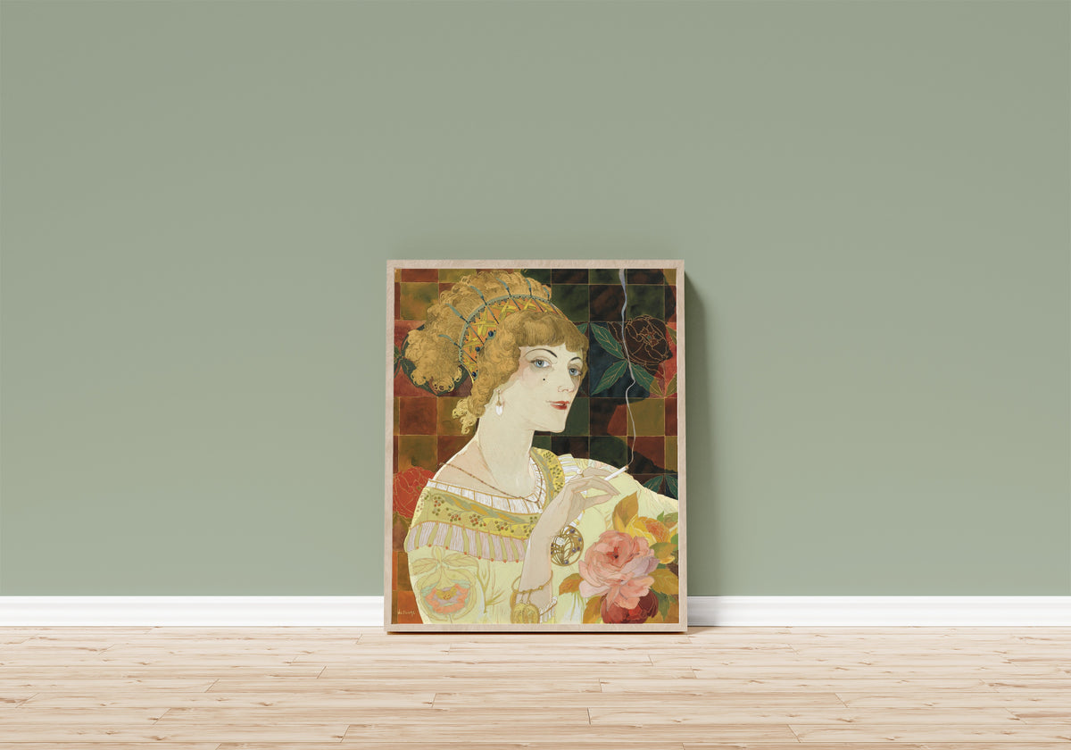 Framed art print of La Fumeuse by Georges de Feure, in a light wood frame leaning on a sage green wall above a wooden floor