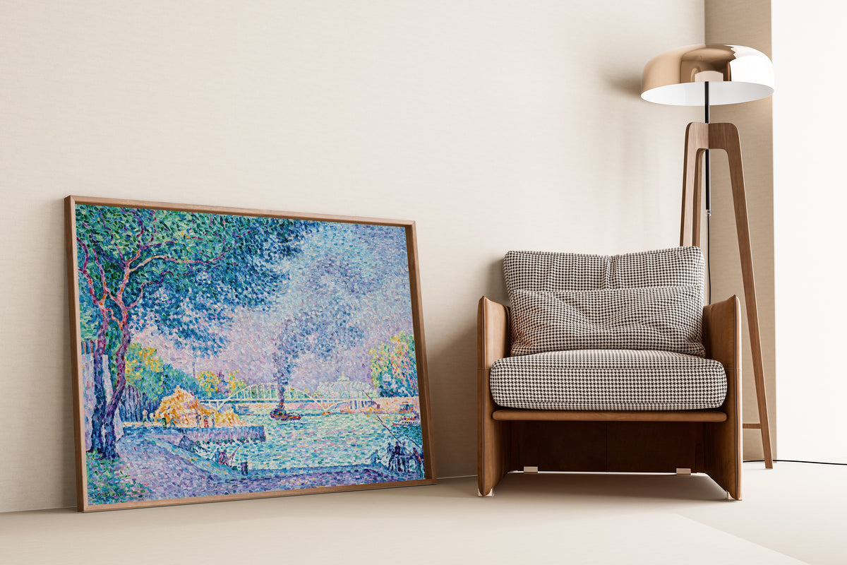 Framed art print of La Passerelle Debilly by Paul Signac, leaning against a wall beside an armchair and a floor lamp