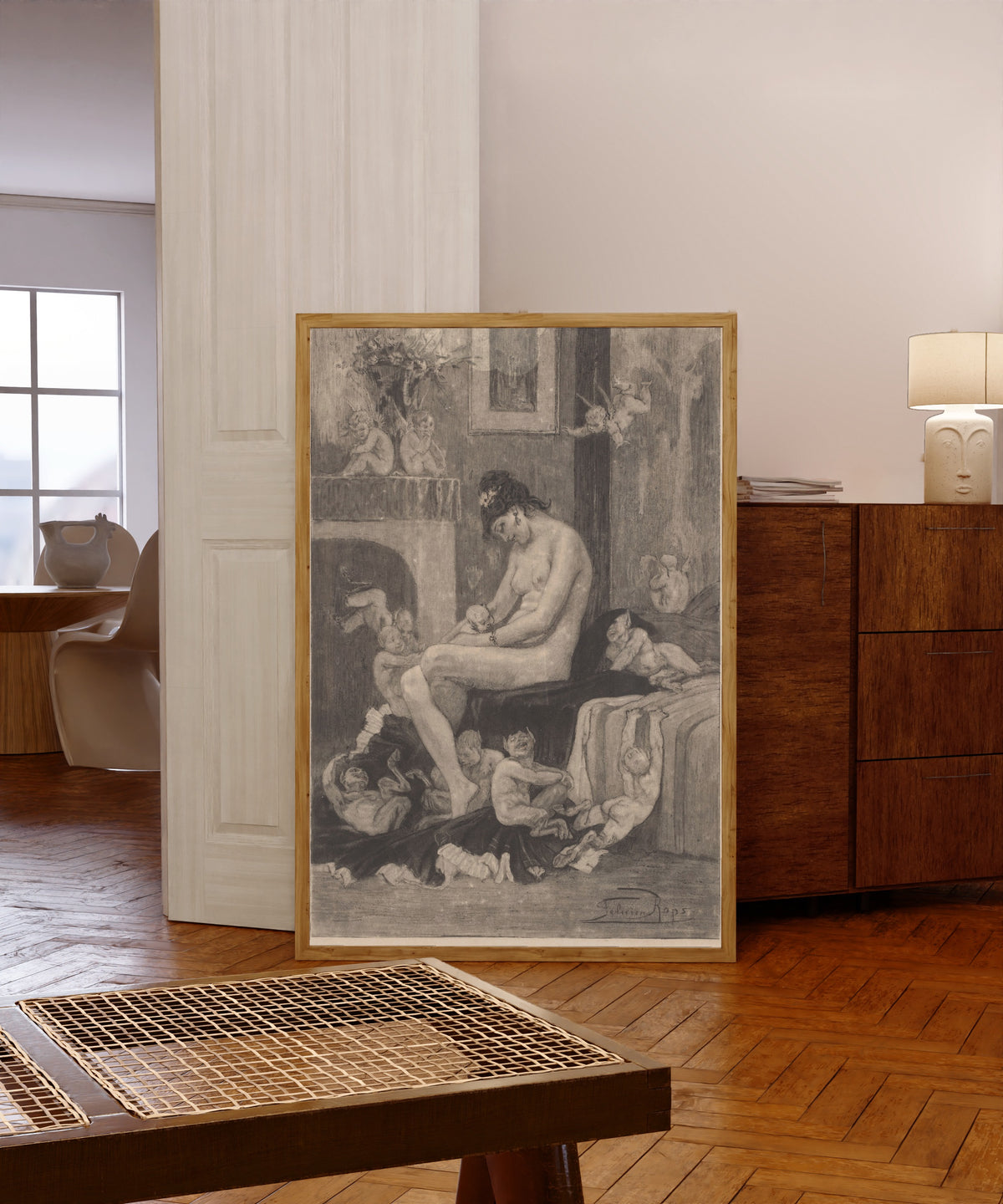 Framed art print of La mère aux Satyrions by Félicien Rops, in a light wood frame leaning in a warm room with a parquet floor