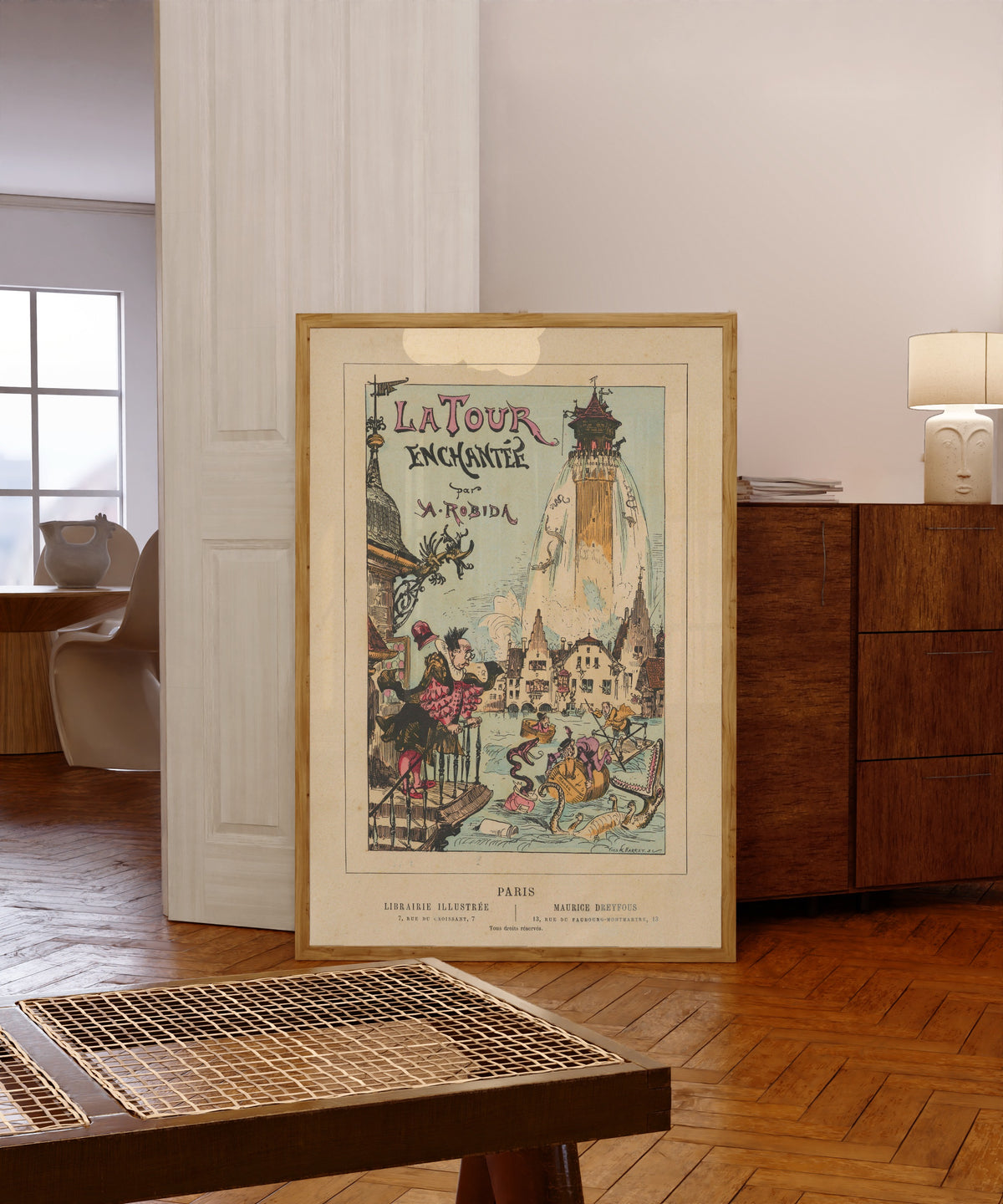 Framed art print of La tour enchantée- Titlepage by Albert Robida, in a light wood frame leaning in a warm room with a parquet floor