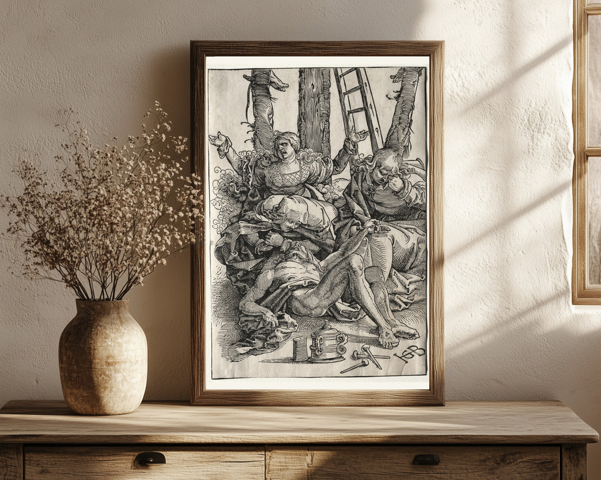 Framed art print of Lamentation by Hans Baldung Grien, in a dark wood frame leaning on a rustic console beside dried flowers