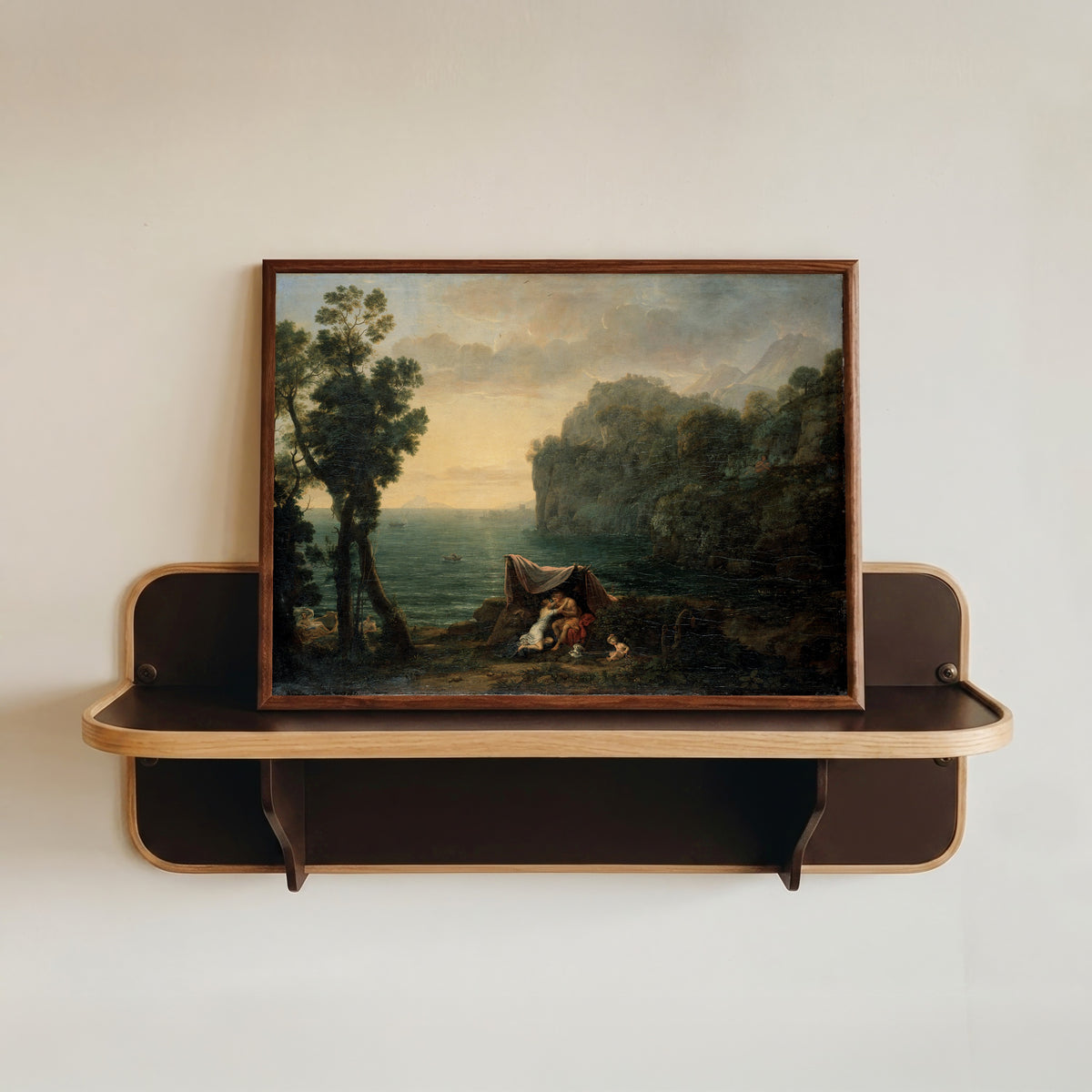 Framed art print of Landscape with Acis and Galatea by Claude Lorrain, in a dark wood frame resting on a wall shelf