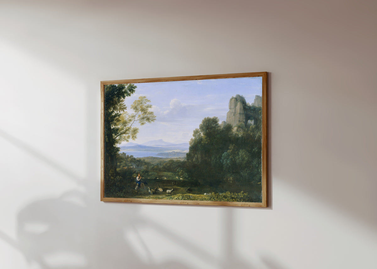 Framed art print of Landscape with Apollo and Mercury by Claude Lorrain, in a light wood frame on a sunlit white wall, seen at a slight angle