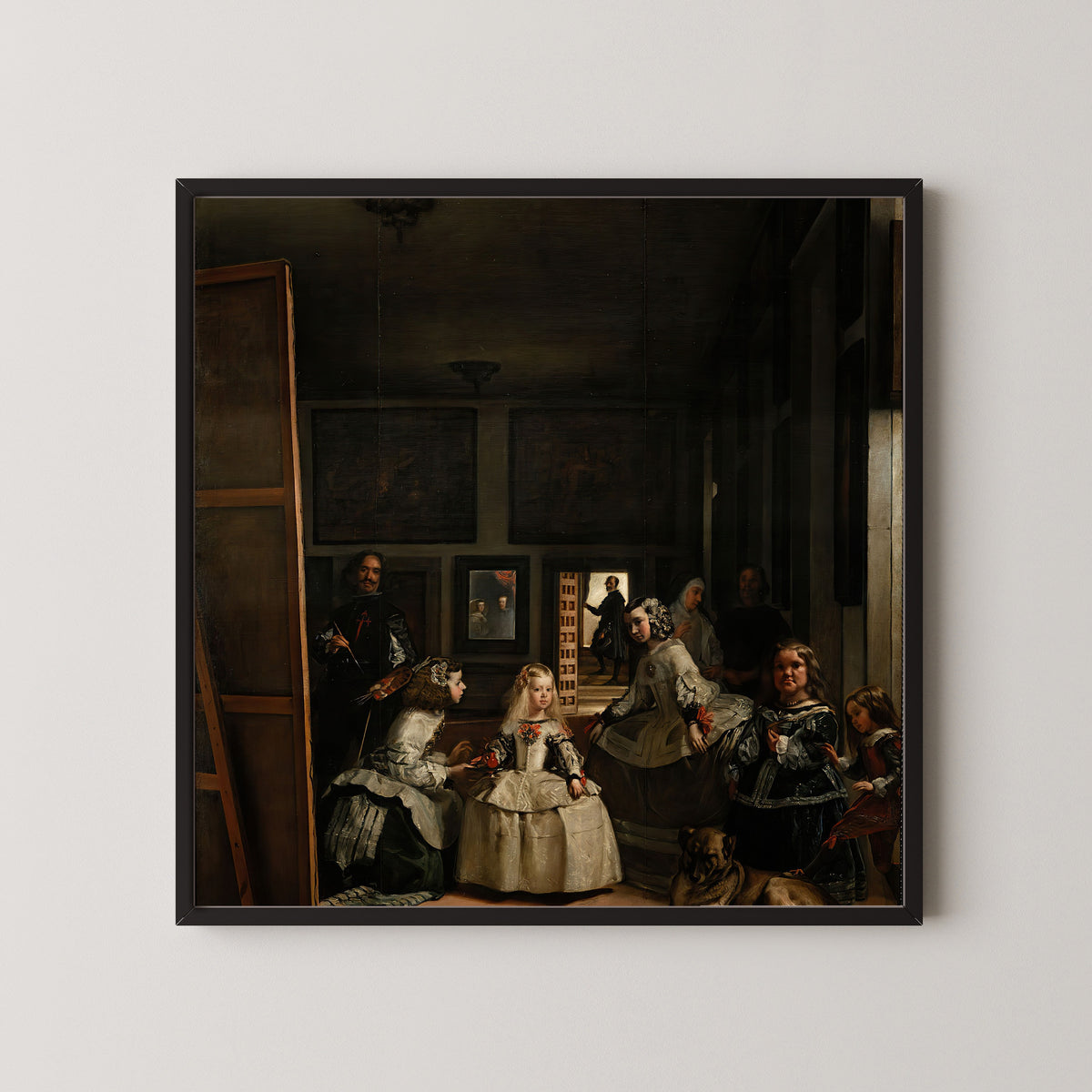 Framed art print of Las Meninas by Diego Velázquez, in a black frame on a pale wall