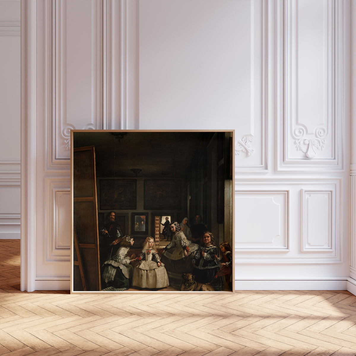Framed art print of Las Meninas by Diego Velázquez, leaning against pale pink panelling on a herringbone floor