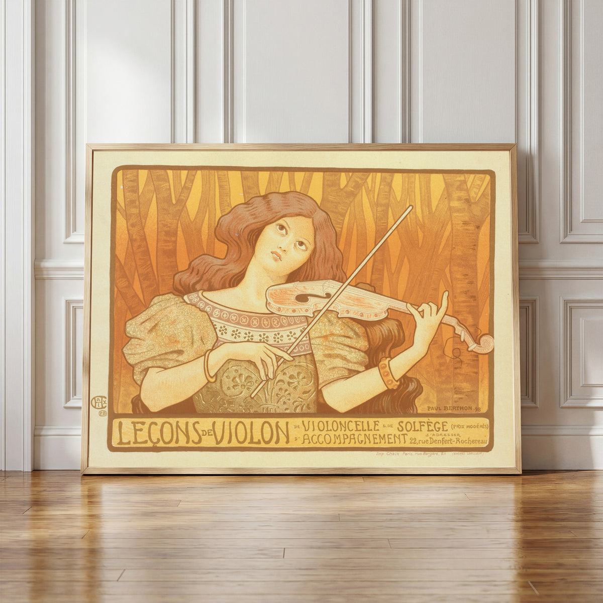 Framed art print of Leçons de Violon by Paul Berthon, in a light wood frame leaning against a panelled white wall