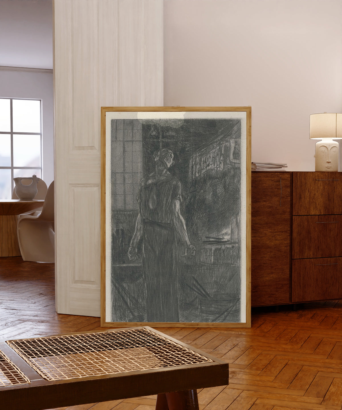 Framed art print of Le pendu dans la forge (2nd state) by Félicien Rops, in a light wood frame leaning in a warm room with a parquet floor