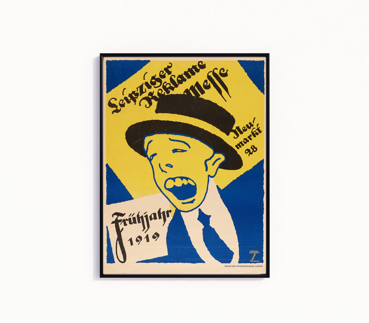 Framed art print of Leipziger Reklame-Messe, Frühjahr 1919 by Ludwig Hohlwein, in a slim black frame on a plain white wall