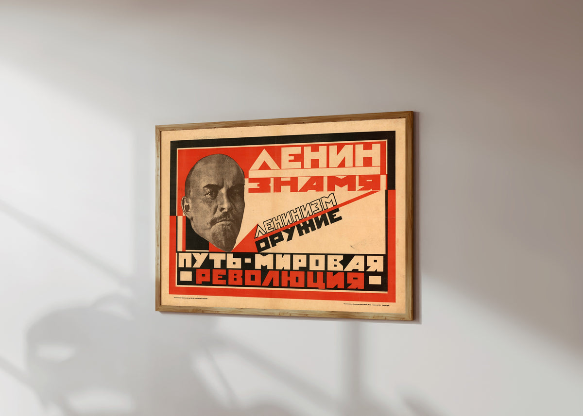 Framed art print of Lenin is the banner. Leninism is the weapon. The path is world…, in a light wood frame on a sunlit white wall, seen at a slight angle
