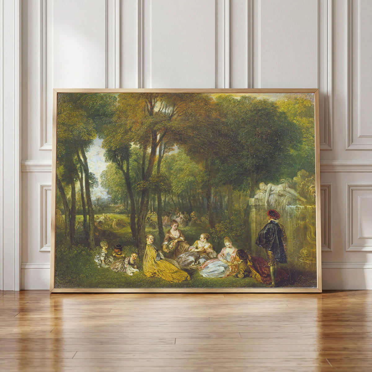 Framed art print of Les Champs Élysées by Jean-Antoine Watteau, in a light wood frame leaning against a panelled white wall