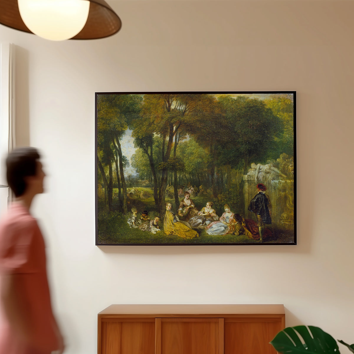 Framed art print of Les Champs Élysées by Jean-Antoine Watteau, in a slim black frame on a warm wall in a sunlit room