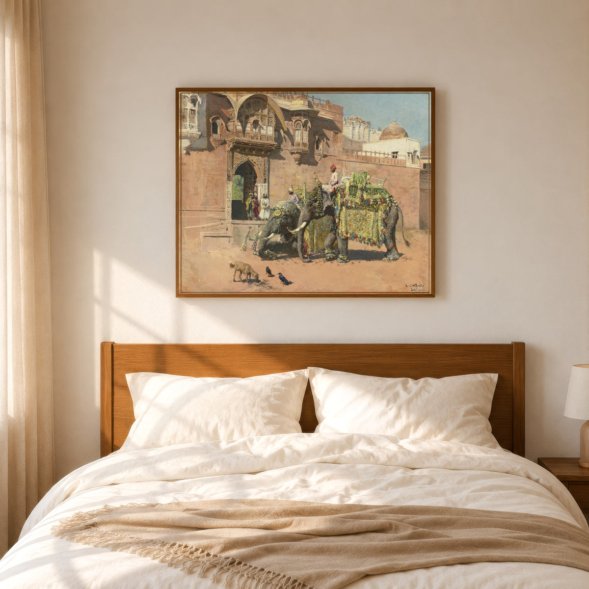 Framed art print of Les éléphants du Rajah de Jodhpore by Edwin Lord Weeks, in a slim wood frame above a bed in a sunlit bedroom