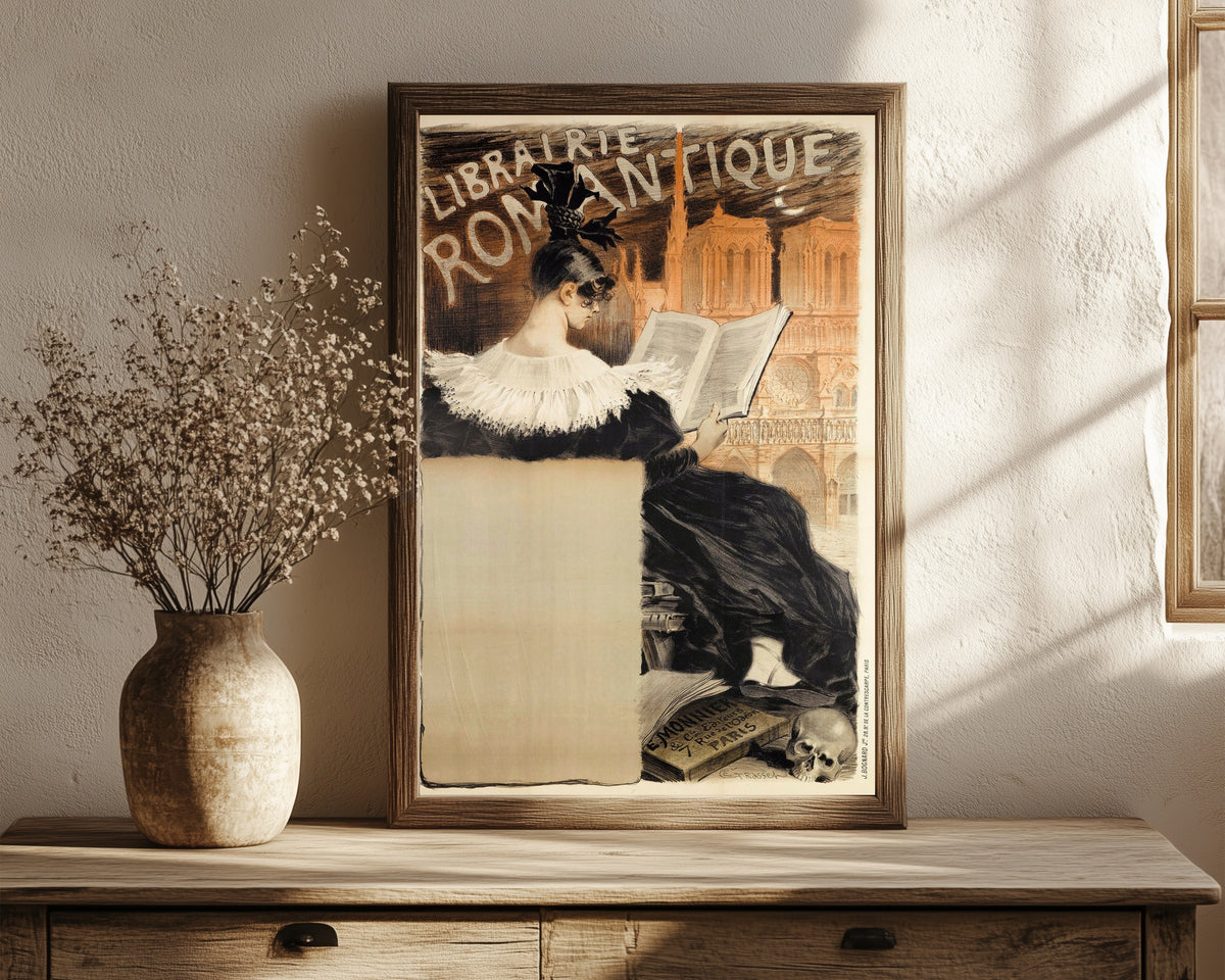 Framed art print of Librairie Romantique by Eugène Grasset, in a dark wood frame leaning on a rustic console beside dried flowers