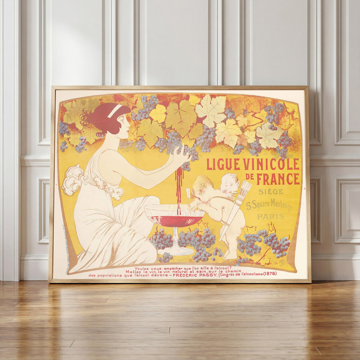 Framed art print of Ligue Vinicole de France by Manuel Orazi, in a light wood frame leaning against a panelled white wall