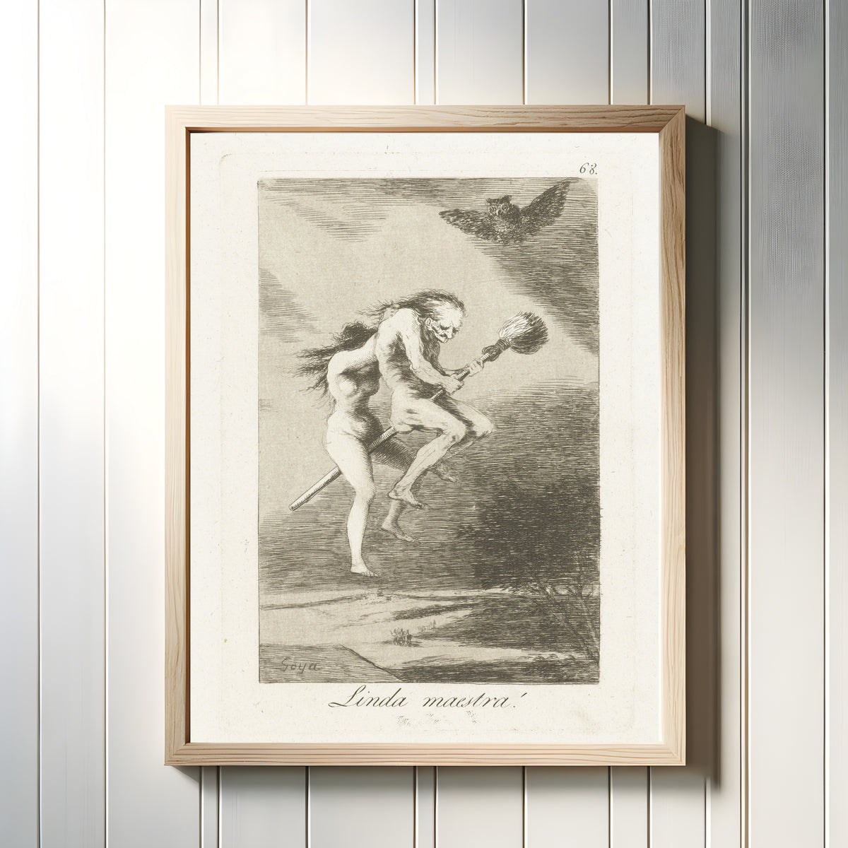 Framed art print of Linda maestra! (A Fine Teacher), Los Caprichos, Plate 68 by Francisco de Goya, in a light wood frame on a white panelled wall