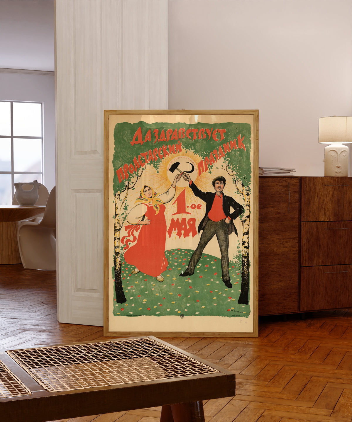 Framed art print of Long live the proletarian holiday, 1 May by Ivan Simakov, in a light wood frame leaning in a warm room with a parquet floor