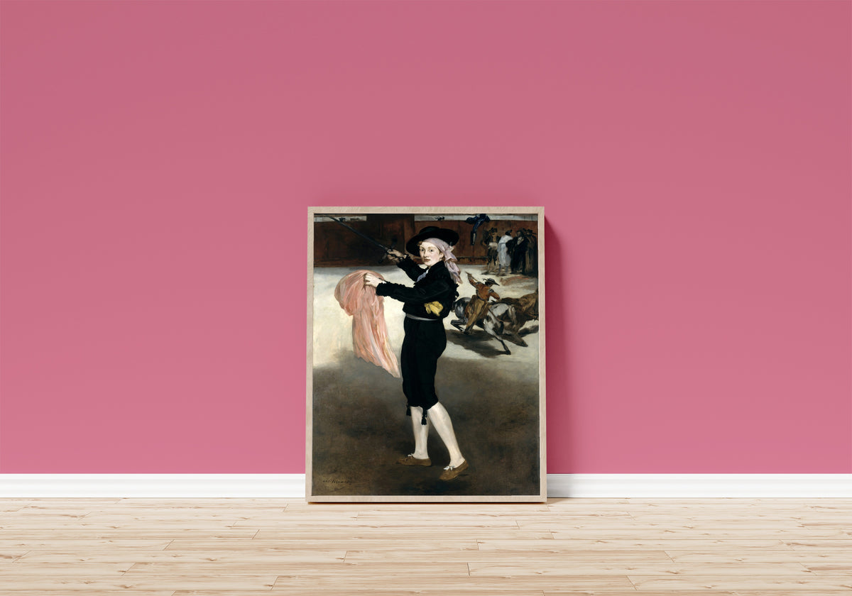 Framed art print of Mademoiselle V. . . in the Costume of an Espada by Édouard Manet, in a light wood frame leaning on a pink wall above a wooden floor