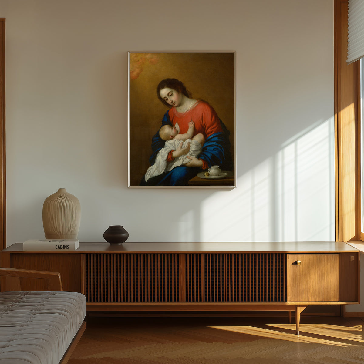 Framed art print of Madonna and Child by Francisco de Zurbarán, in a thin light frame on a sunlit wall above a wooden sideboard