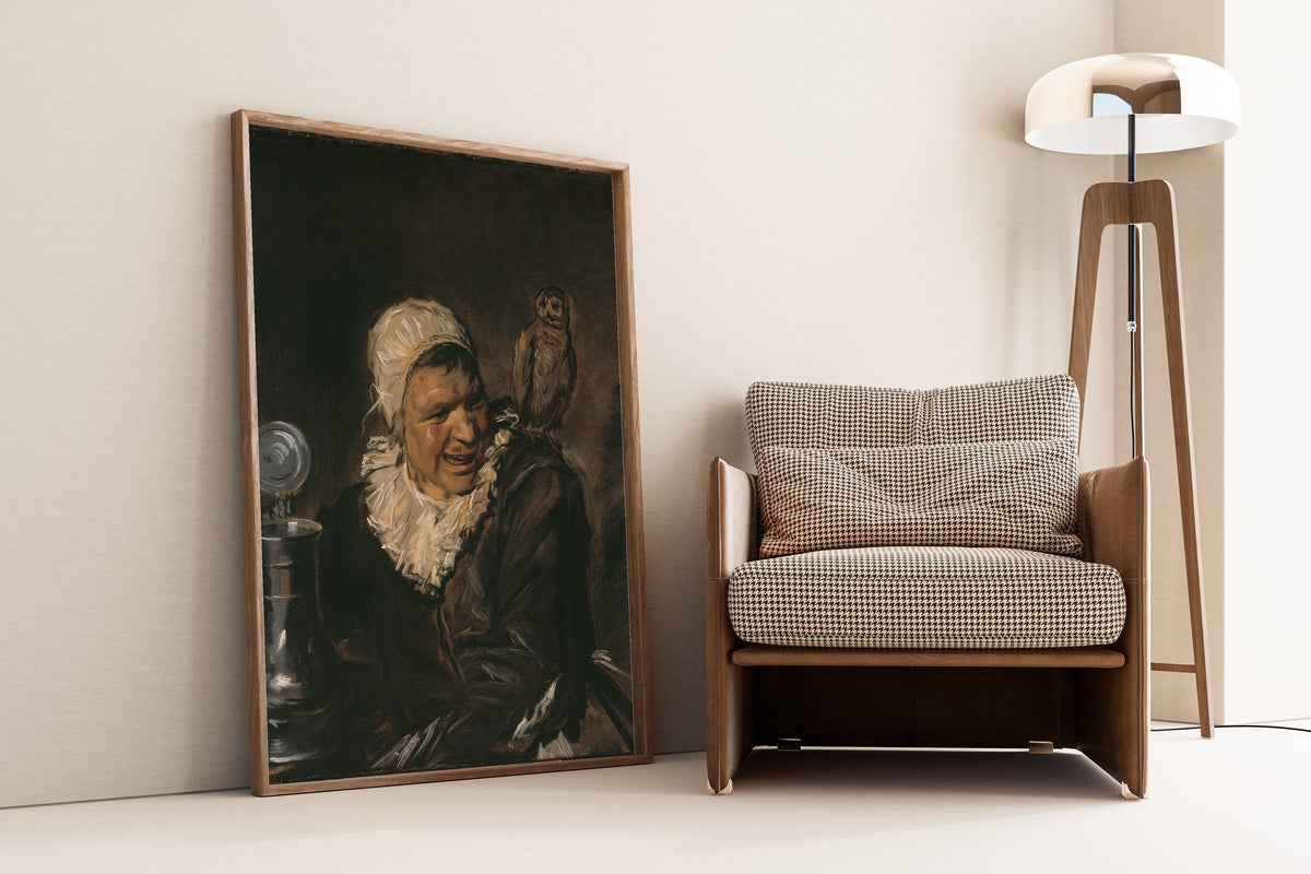 Framed art print of Malle Babbe by Frans Hals, leaning against a wall beside an armchair and a floor lamp