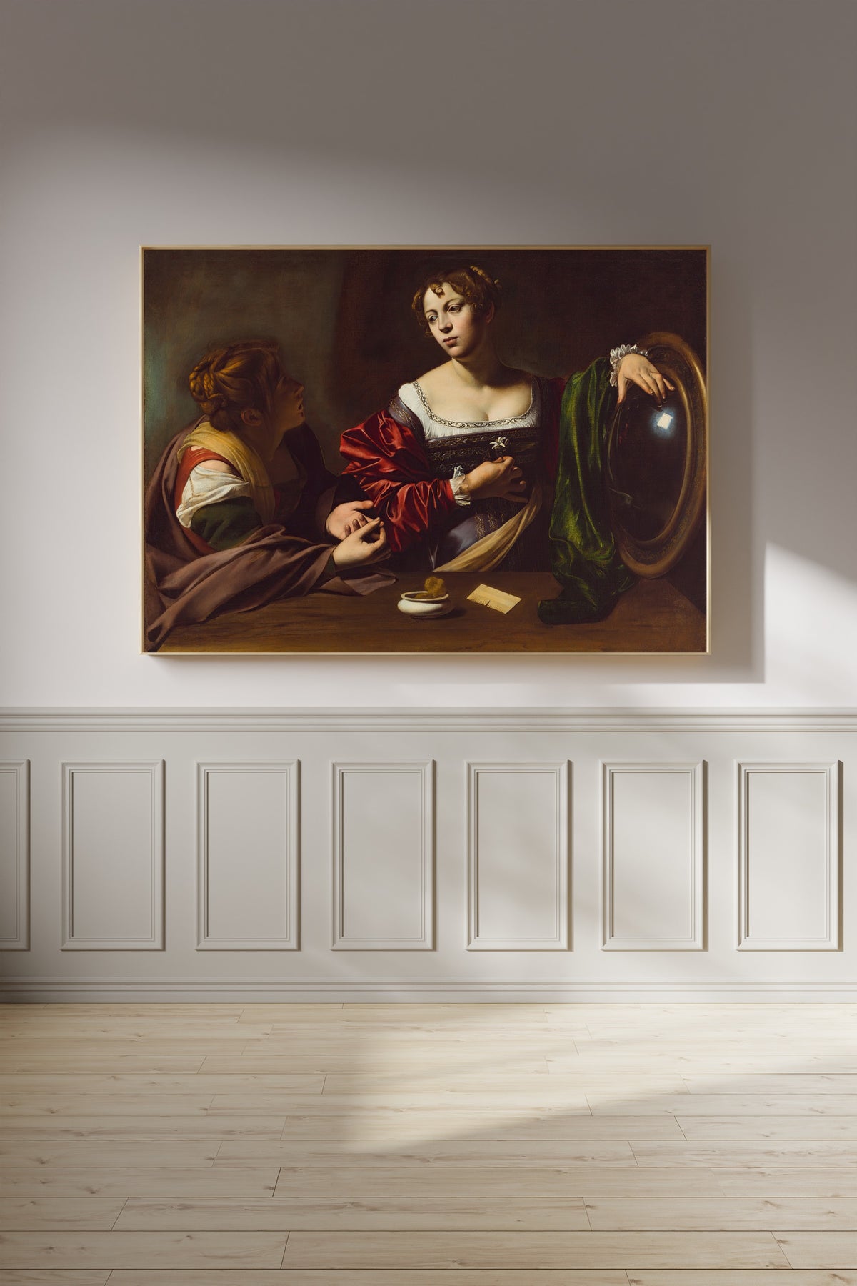 Framed art print of Martha and Mary Magdalene by Caravaggio, on a panelled wall in afternoon light