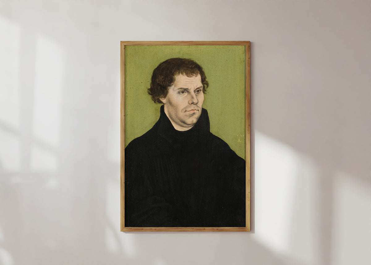 Framed art print of Martin Luther by Lucas Cranach the Elder, in a light wood frame on a sunlit white wall