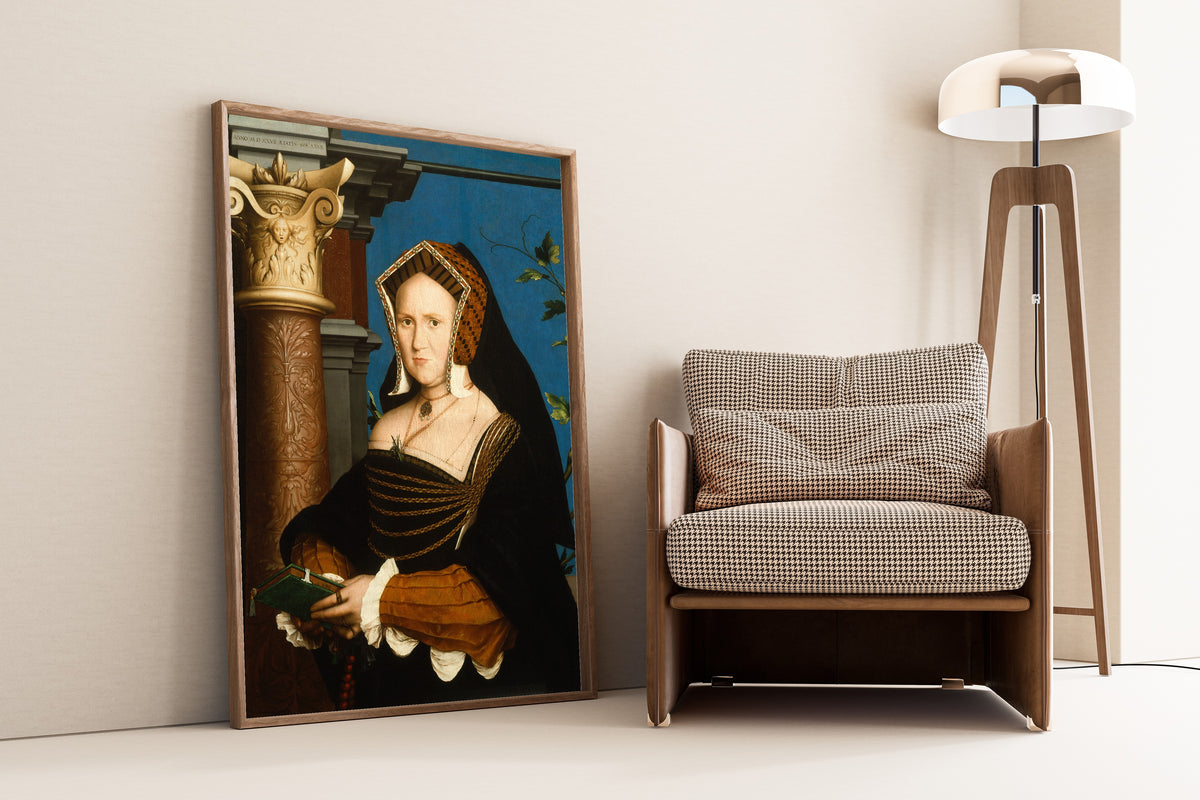 Framed art print of Mary, Lady Guildford by Hans Holbein the Younger, leaning against a wall beside an armchair and a floor lamp