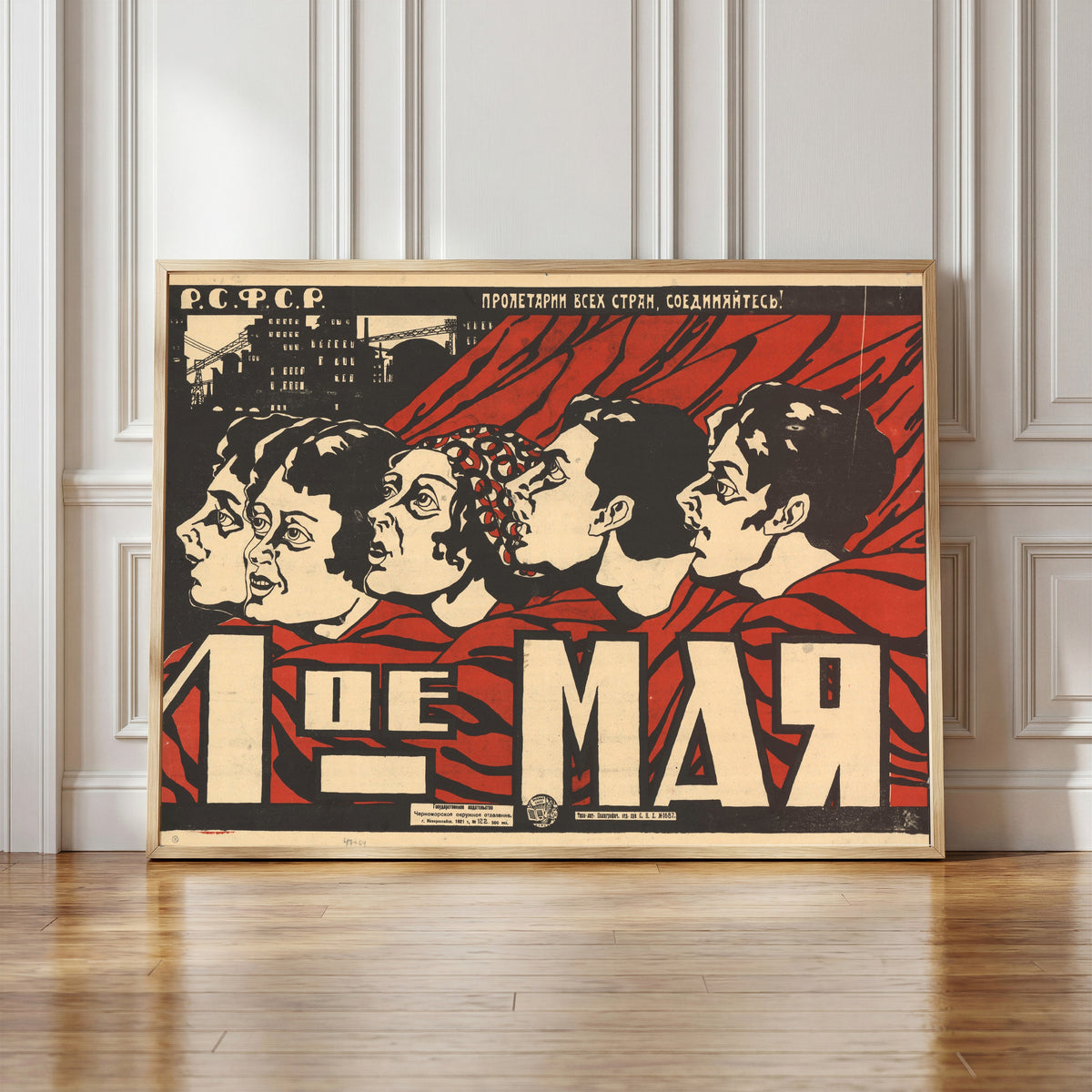 Framed art print of May 1st, in a light wood frame leaning against a panelled white wall