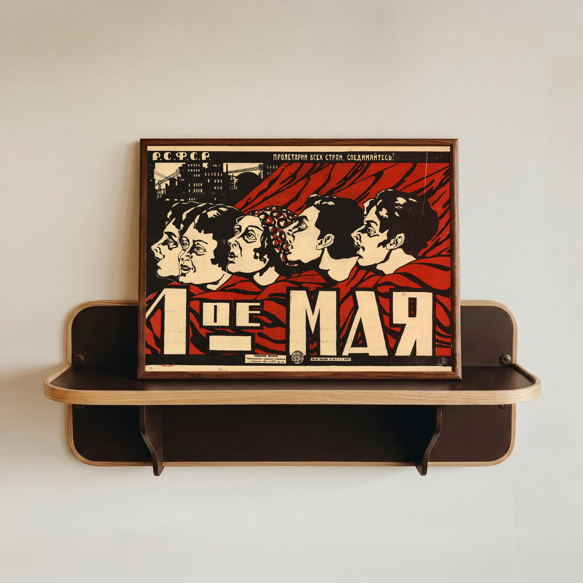 Framed art print of May 1st, in a dark wood frame resting on a wall shelf
