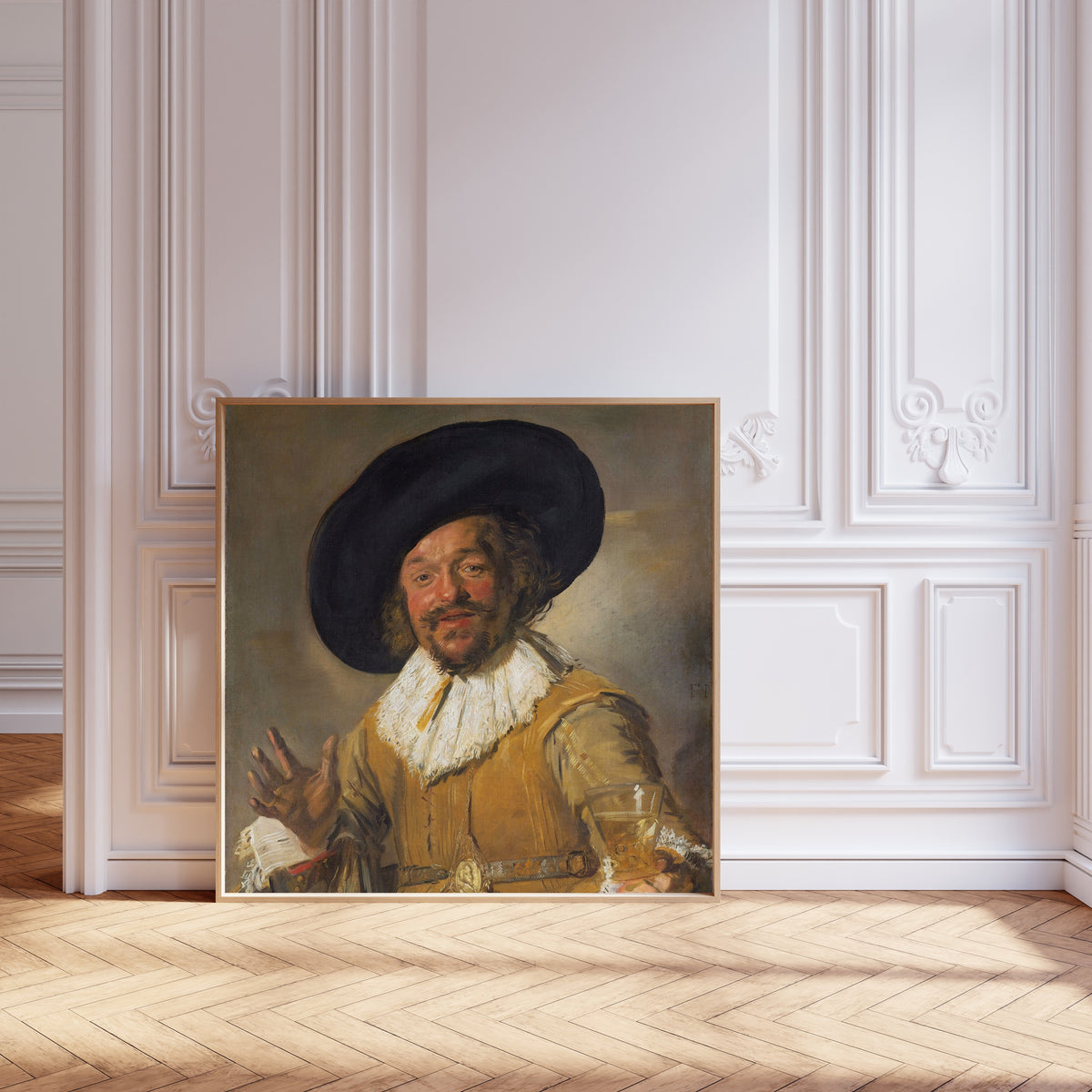 Framed art print of Merry Drinker by Frans Hals, leaning against pale pink panelling on a herringbone floor