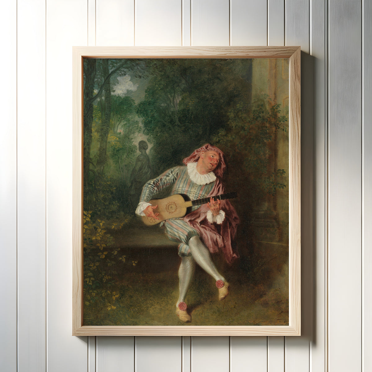Framed art print of Mezzetin by Jean-Antoine Watteau, in a light wood frame on a white panelled wall