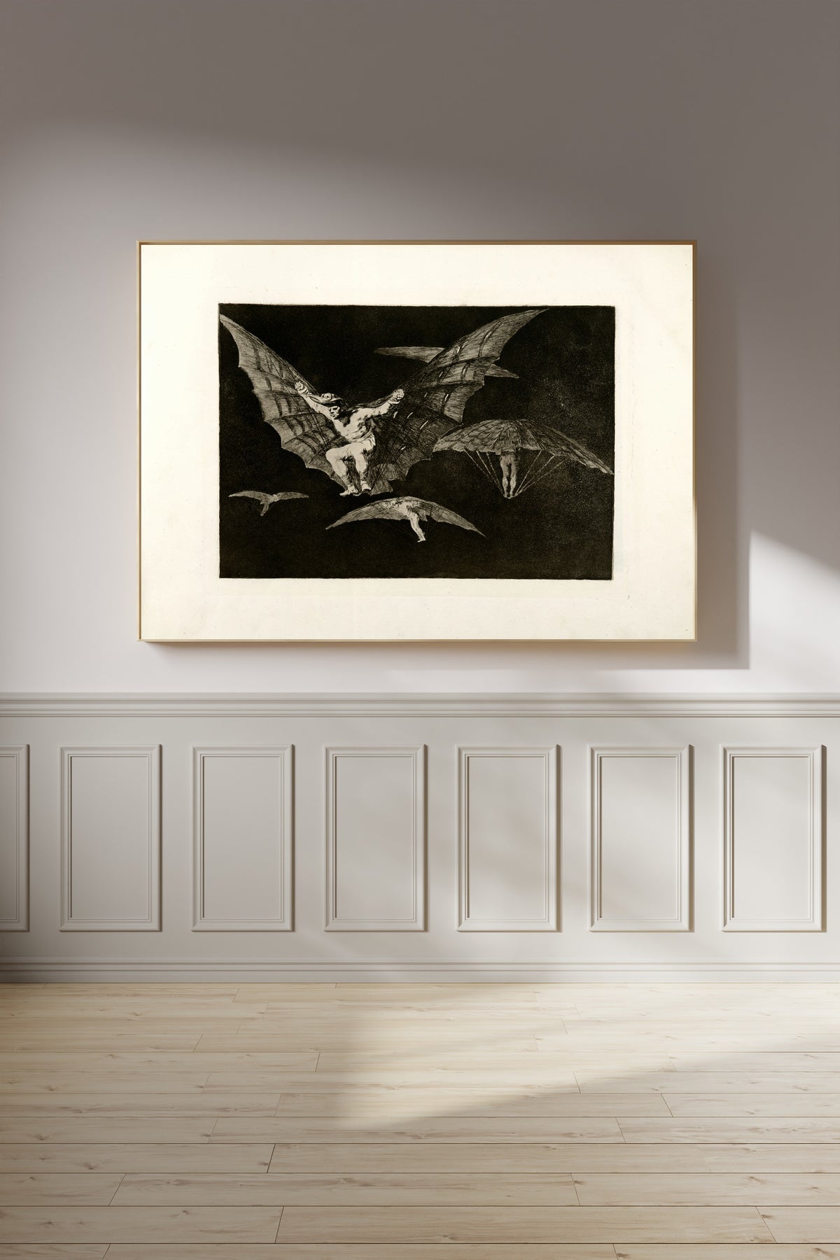 Framed art print of Modo de volar (A Way of Flying), from Los Disparates by Francisco de Goya, on a panelled wall in afternoon light